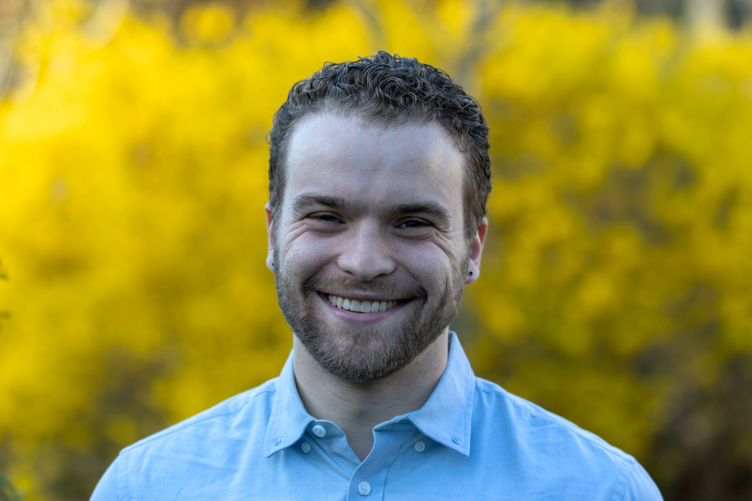 A person wearing a light blue shirt and smiling.