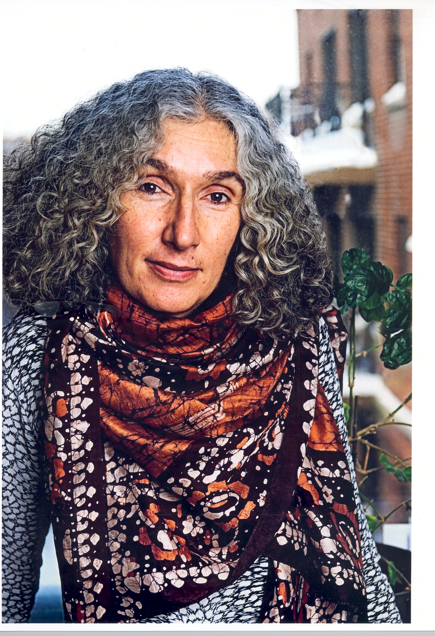 a woman with grey hair smiling, wearing a colorful scarf